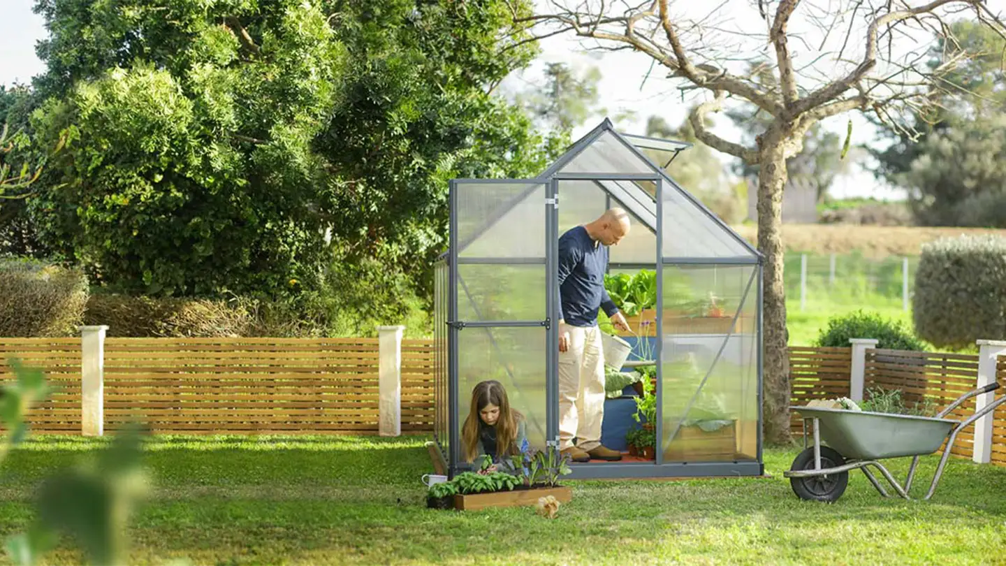 Canopia drivhus i en have, hvor en far og datter planter planter.